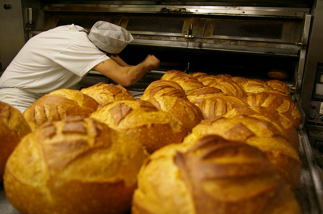 Foto mostra padeiro retirando pães fresquinhos do forno