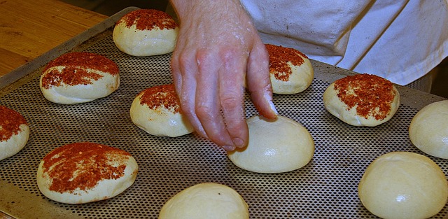 Foto mostra padeiro preparando vários pães antes de colocar para assar